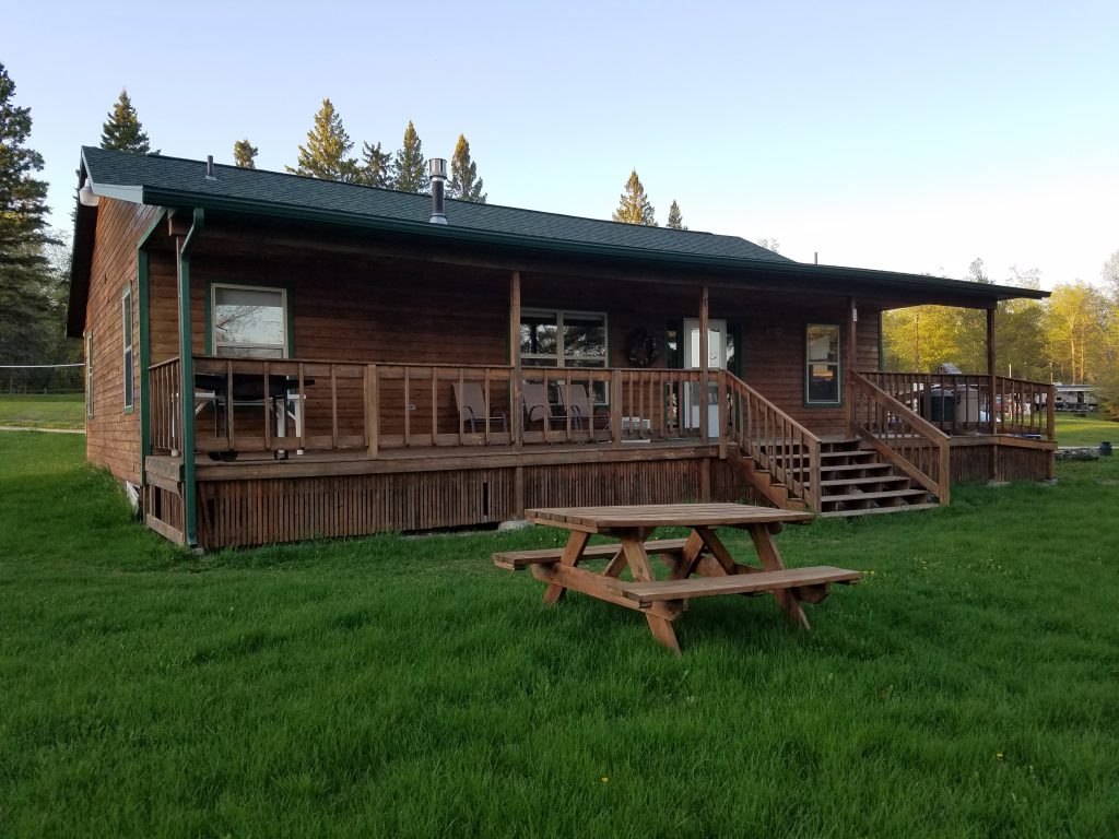 brown lakeside cabin rental with picnic table in front and seating area on porch