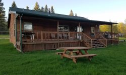 brown lakeside cabin rental with picnic table in front and seating area on porch