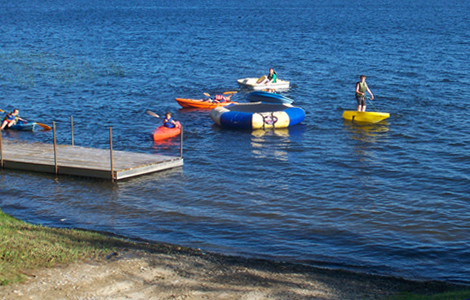 several children in row boats with oars paddling in lake near dock