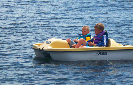 two young boys in yellow and white paddleboat in water